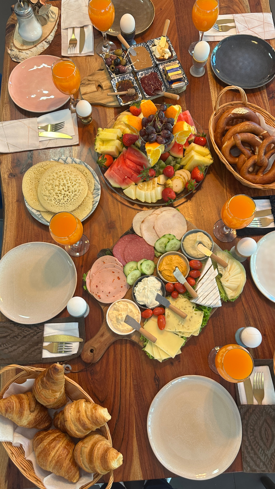 Frühstücksbrett mit Käseauswahl, Aufschnitt, Hummus, Gemüse und frischen Croissants